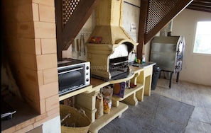 Una cocina rústica con horno de leña, tostador y pileta.