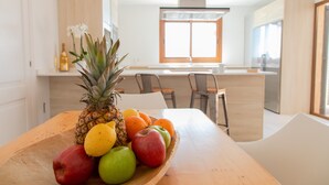 Une cuisine moderne avec une table en bois sur laquelle sont disposés des fruits et une bouteille.