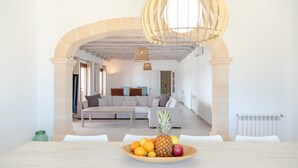 Un salon moderne avec un canapé, une table à manger ornée de fruits et une structure de plafond en bois originale.
