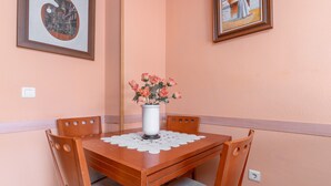 Una mesa de comedor con un florero, sillas de madera y cuadros en las paredes.