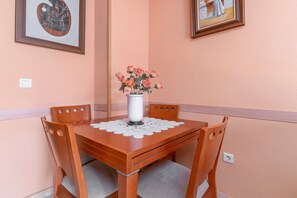 A dining table with a vase of flowers, wooden chairs, and framed artwork on the walls. - Apartment 'Piso El Morche' with Shared Pool, Private Terrace and Wi-Fi (Torrox Costa)