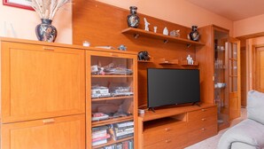 Un mueble de madera con televisor de pantalla plana, estanterías, objetos decorativos y un sofá.