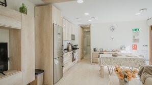 A modern kitchen with wooden cabinets, a refrigerator, and a dining area with a table and chairs.