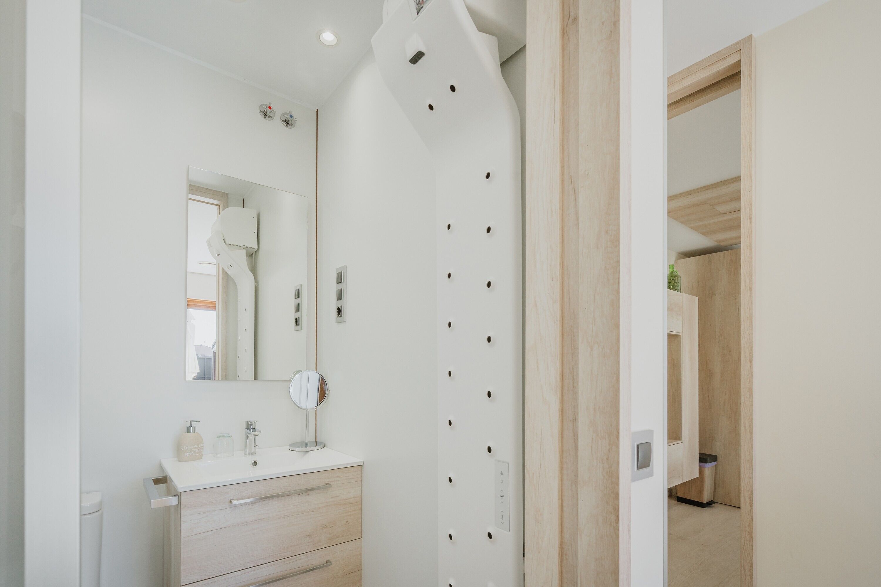 A bathroom with a white vanity, a mirror, and a towel rack.