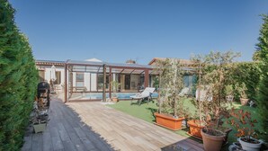 A patio with a pool, potted plants, and a lounge chair.