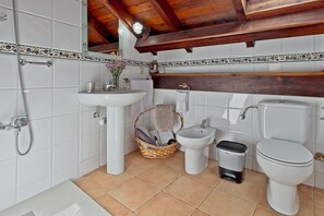 Un baño con lavamanos, bidé, inodoro y un cubo de basura.