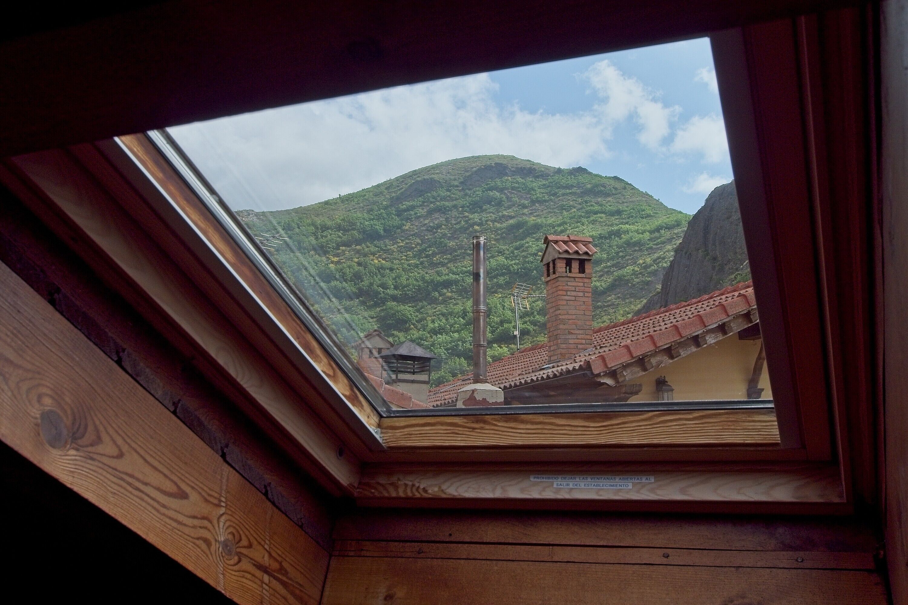 Un tragaluz con vistas a una montaña y una chimenea de ladrillo.