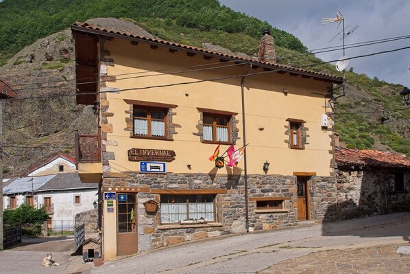 Un edificio de piedra con un letrero que dice 'EL INVERMAL' y una bandera.
