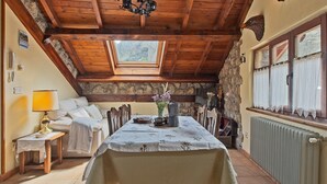 Un rincón comedor acogedor con una mesa de madera, sillas, una lámpara y vistas a través de un tragaluz.