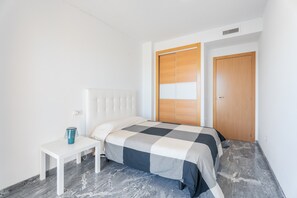 Un dormitorio con cama, mesita de noche, armario y suelo de mármol.