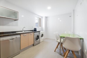 Una cocina moderna equipada con lavavajillas, lavadora y comedor con mesa y sillas.