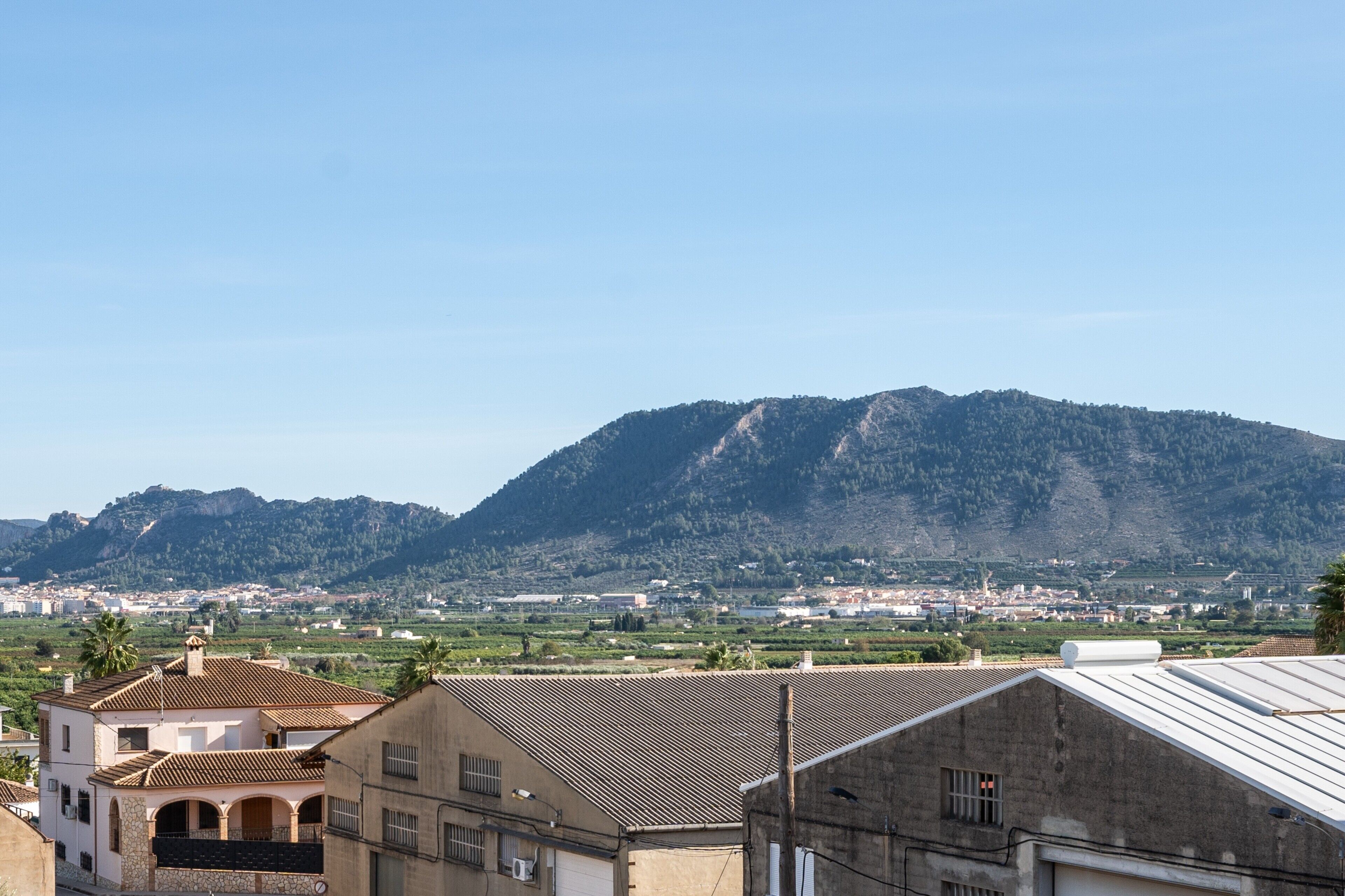 Un edificio con techo de tejas, pared de piedra y vista a la montaña.