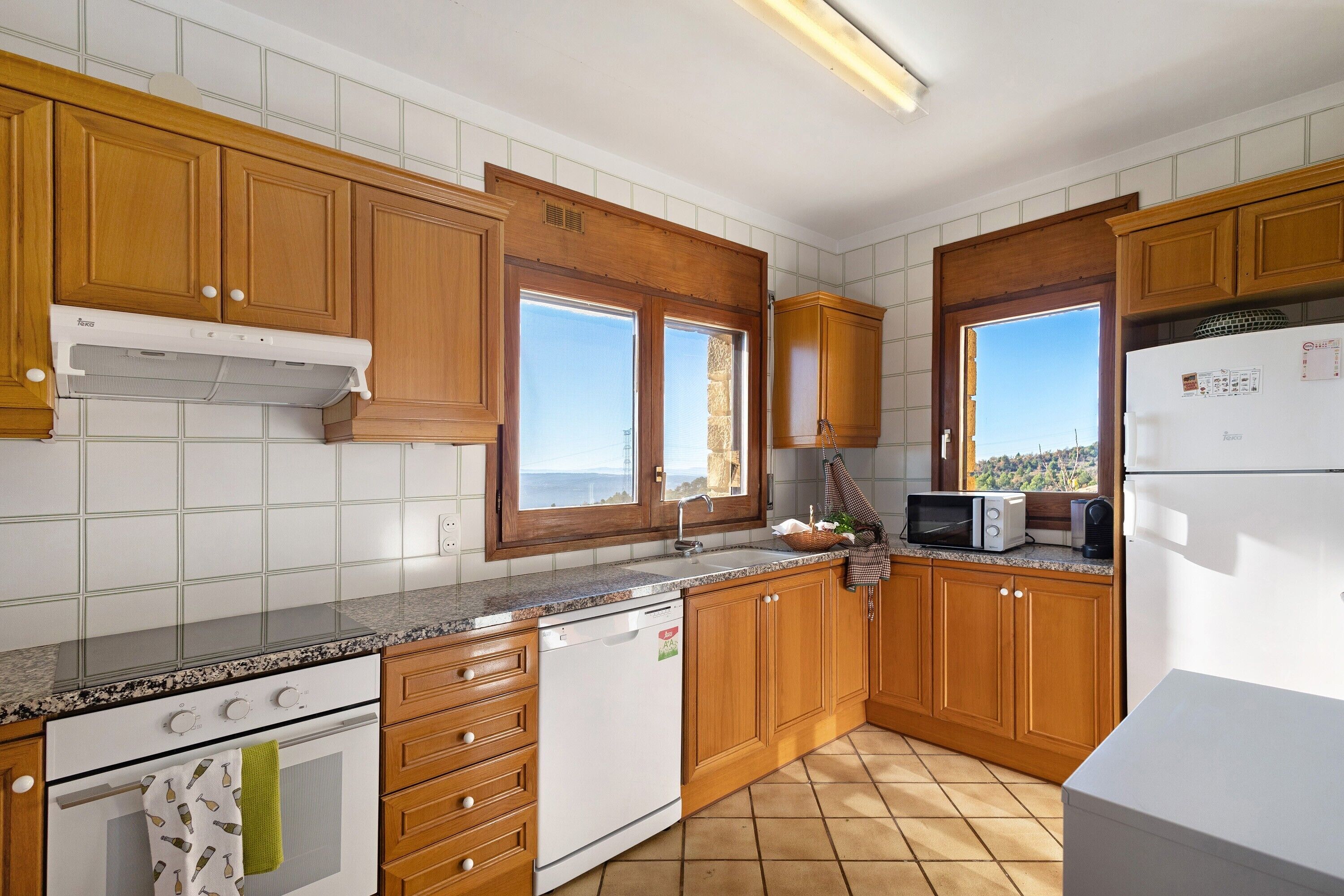 A kitchen with wooden cabinets, a white dishwasher, a microwave, and a refrigerator.
