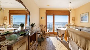 A room with a balcony, a dining table, a chair, a bed, a dresser, and a mirror.