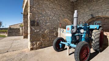 A blue tractor parked outside a stone building with a metal gate.