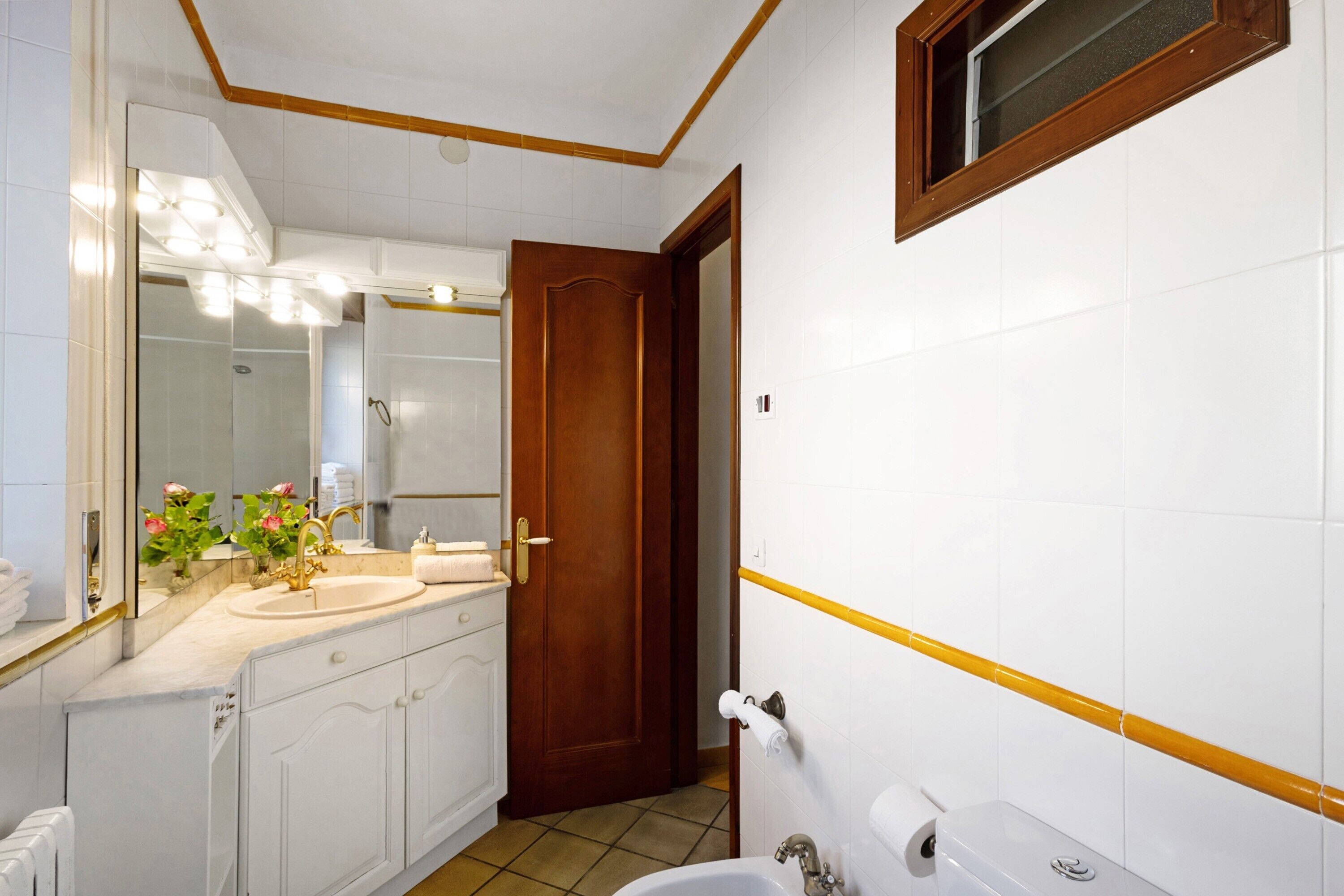 A bathroom with a sink, mirror, toilet, and shower.
