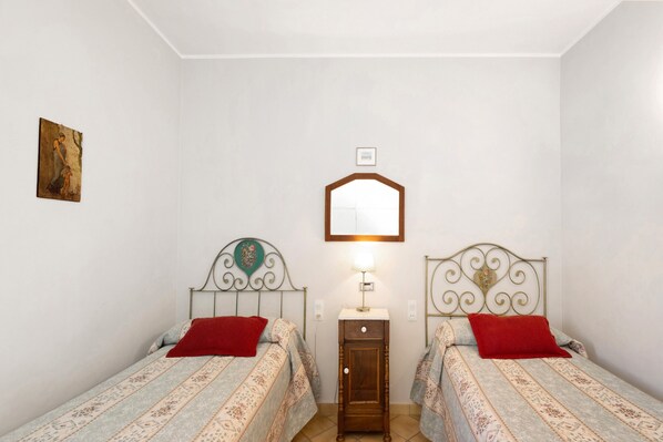 Un dormitorio con dos camas, una mesita de noche, un espejo y un cuadro en la pared.
