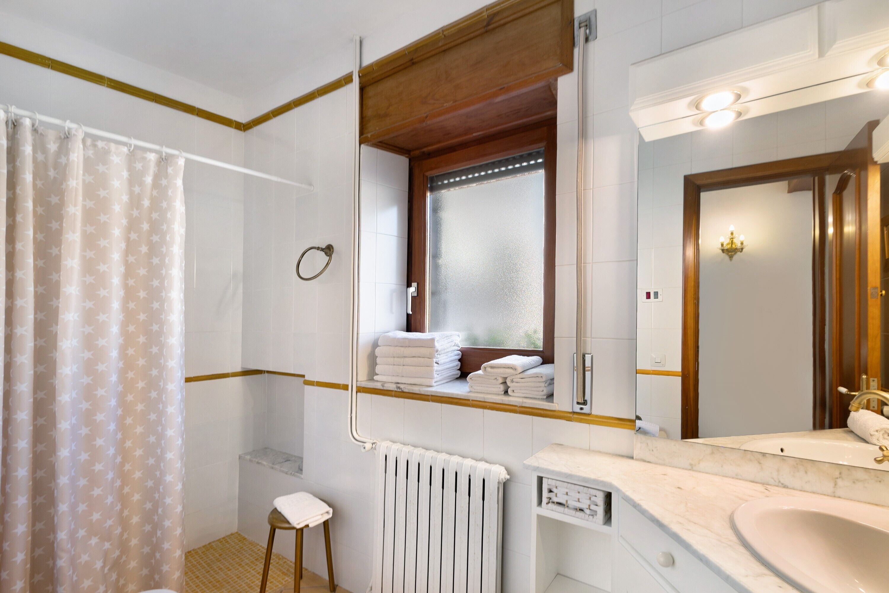 Un bagno con doccia, un water, un lavandino e uno specchio.