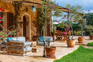 Un patio con mobiliario exterior, plantas en macetas y una pared de piedra.