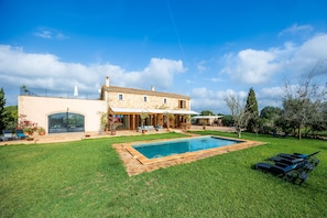 Ein Haus mit Swimmingpool, einer überdachten Terrasse und einem eingezäunten Garten.