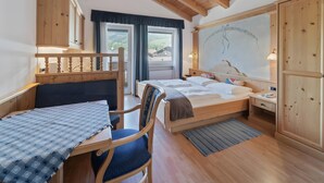 Habitació amb estructura de fusta, un llit, un escriptori i una cadira.