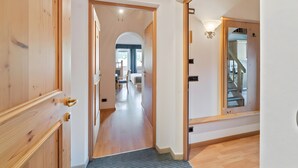 Un passadís amb portes de fusta, una catifa i una escala que porta a una altra habitació.
