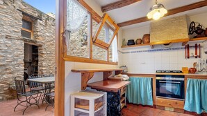A rustic kitchen with stone walls, a wooden table, and a built-in oven.