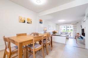 A modern living room with a sofa, a dining table with chairs, and artwork on the walls. - Apartment 'Cala Egos Villa - S'Estel' with Shared Pool, Wi-Fi and Air Conditioning (Cala D'or)