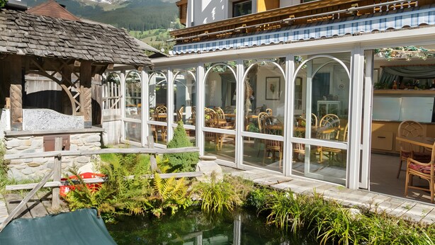 Un chalet doté d’un espace repas entièrement vitré, d’une structure en pierre et d’un étang.