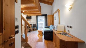 Un intérieur en bois comprenant un escalier, un canapé, une table et un coin cuisine.