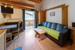 Una habitación acogedora con sofá, mesa, silla, televisión y vistas al exterior.