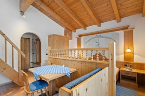 A wooden interior with a staircase, a dining area with a checkered tablecloth, and a bench.