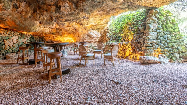 An indoor dining area with stone walls, wooden furniture, and a gravel floor. - Country House 'S' Oratge' with Mountain View, Shared Pool and Wi-Fi (Illes Balears)