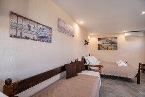 Une chambre avec deux lits, une tête de lit en bois et des œuvres d’art accrochées aux murs.