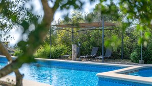 A swimming pool with lounge chairs and a pergola, surrounded by greenery. - Country House 'Ses Estaques' with Mountain View, Shared Pool and Wi-Fi (Illes Balears)