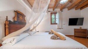 A bedroom with a wooden bed, a TV, a window, and a wooden dresser. - Country House 'Ses Estaques' with Mountain View, Shared Pool and Wi-Fi (Illes Balears)