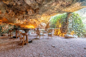 Un espace de restauration intérieur avec des murs en pierre, des meubles en bois et un sol recouvert de gravier.