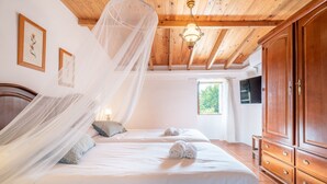Een slaapkamer met twee bedden, een houten garderobe en een plafond met zichtbare balken.