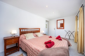 Une chambre à coucher avec un lit, des tables de chevet, un miroir et un étendoir.