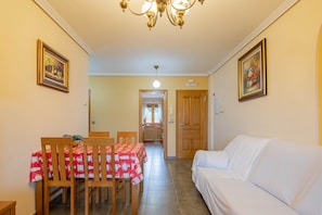 A dining area with a table and chairs, a sofa, and a hallway leading to a kitchen. - 'Apartment 12' with Shared Pool, Private Terrace and Wi-Fi (Cangas)