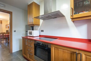 A kitchen with wooden cabinets, a red countertop, a microwave, and an oven. - 'Apartment 12' with Shared Pool, Private Terrace and Wi-Fi (Cangas)