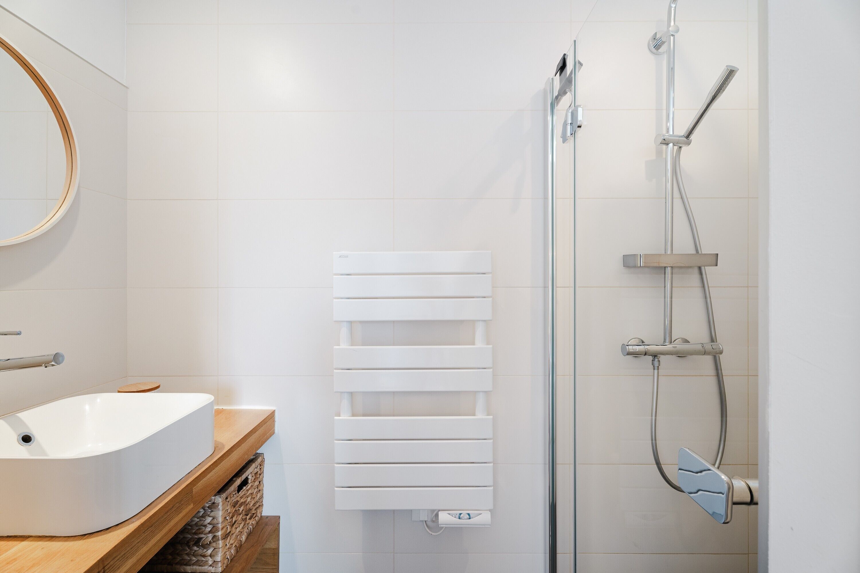 Een badkamer met een wit wastafel, een spiegel, een handdoekhouder en een douche.