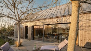 A modern house with a patio, lounge chairs, and a dining area. - Holiday Home 'Mézon Ermine' with Terrace, Private Garden and Wi-Fi (Saint-Cast-le-Guildo)