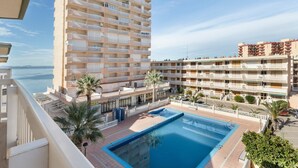 Um hotel com piscina, varandas e vista para o mar.