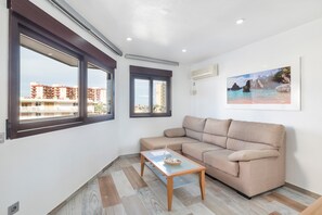 Ein Wohnzimmer mit einer Couch, einem Couchtisch und Blick auf Gebäude durch große Fenster.