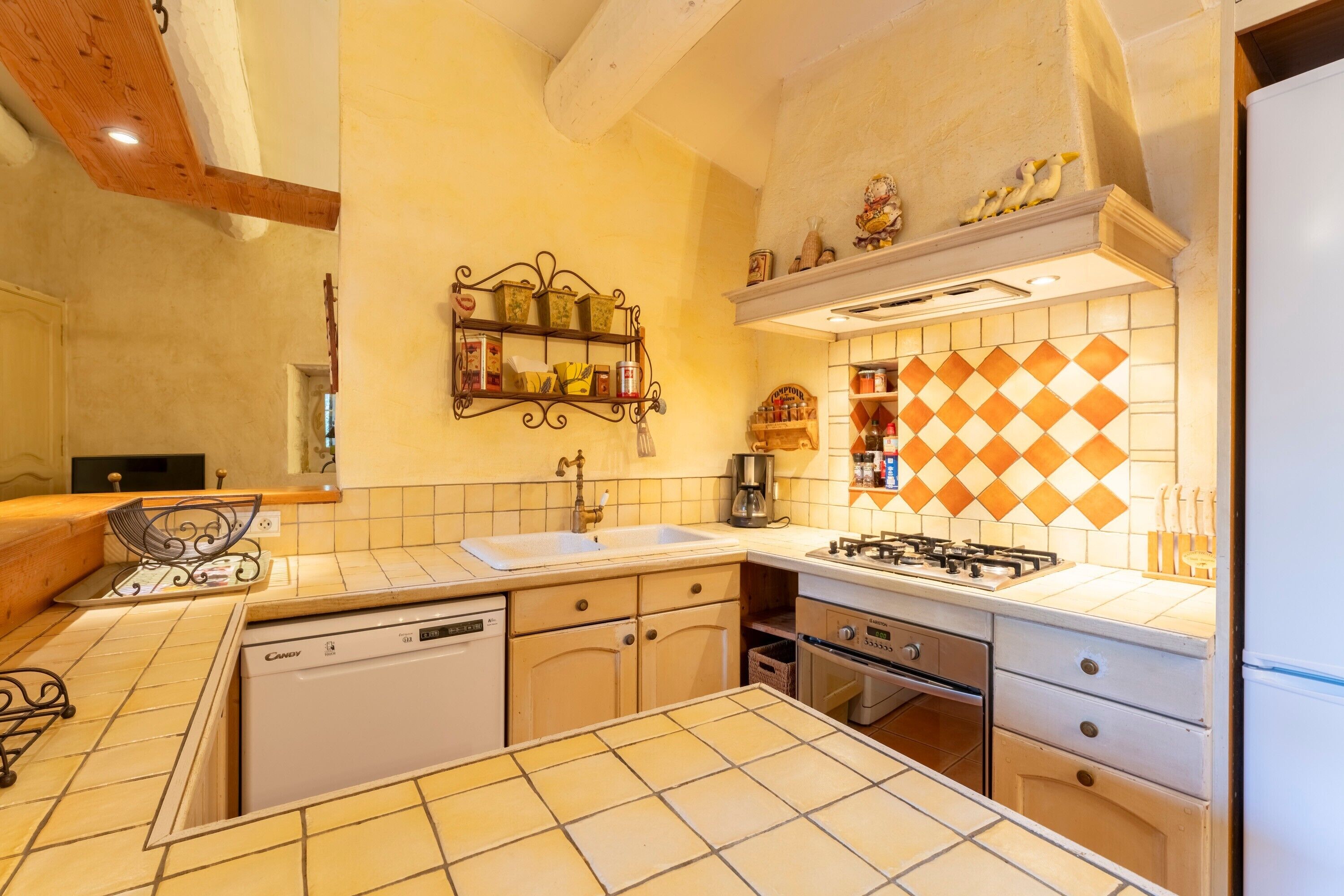 Una cocina con lavavajillas, estufa, fregadero y una repisa decorativa.