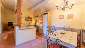 A kitchen with a dining area, a chandelier, and a refrigerator. - Provençal House “Le Patio” – 2 Bedrooms, Private Terrace, Pool & Garden in Velleron (Velleron)