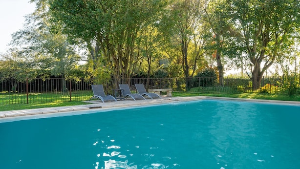 A swimming pool with lounge chairs and a fence, surrounded by trees. - Provençal House “Le Patio” – 2 Bedrooms, Private Terrace, Pool & Garden in Velleron (Velleron)