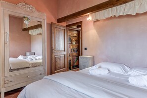 Une chambre à coucher avec un lit, une armoire, un miroir et un petit meuble.