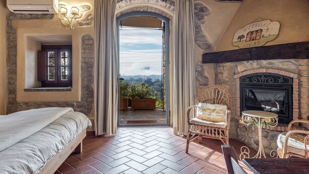 A bedroom with a bed, a fireplace, and a view through an open door. - Apartment 'Il Nido' with Shared Pool, Wi-Fi and Air Conditioning (Pian di Scò)